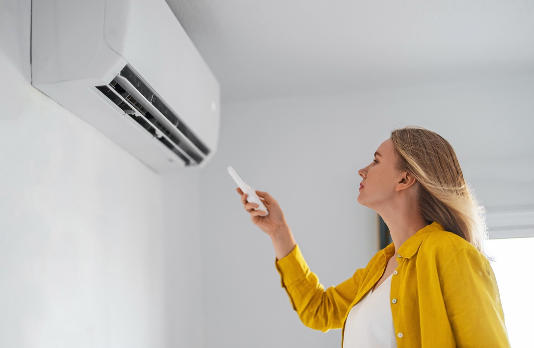 Woman controlling temperature in single room with visible ductless mini split AC