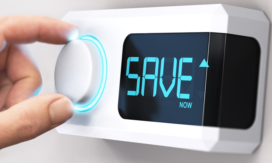 Person using thermostat with words "SAVE NOW" displayed on screen to symbolize benefits of multi-zone heating