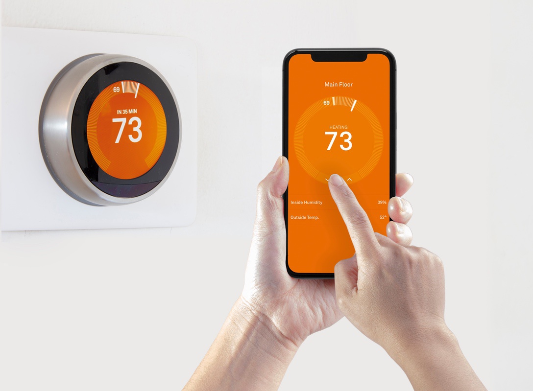 Person using smartphone to control thermostat for main floor of home with partitioned ducts for multi-zone heating